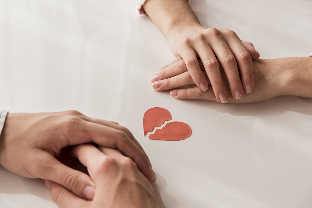 dos personas frente a frente ante un corazón roto