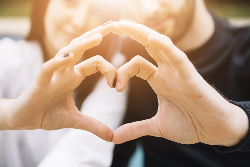 Pareja hace la forma de corazón con sus manos