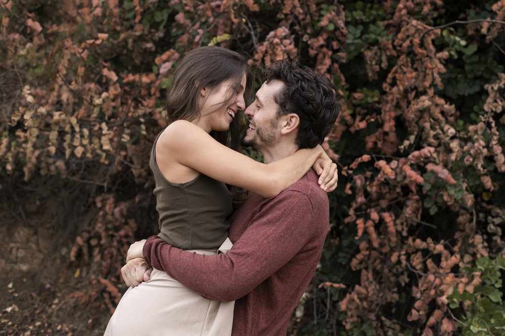 Pareja se abraza con fondo de flores